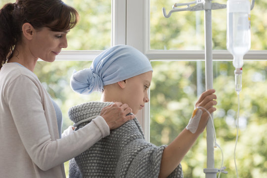 Caregiver Hugging Sick Kid With Headscarf Holding Drip In The Hospital