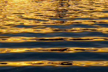 Parallel lines of water wave with sunlight refection at sunset