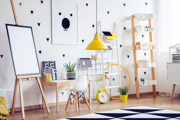 Bright scandinavian kid's playroom with wooden furniture and black and white poster on the wall