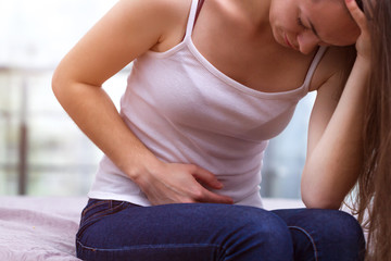 Young woman feels bad and experiences abdominal pain during the period of PMS and menstruation. Painful menstruation. Inflammation and Bladder Infection