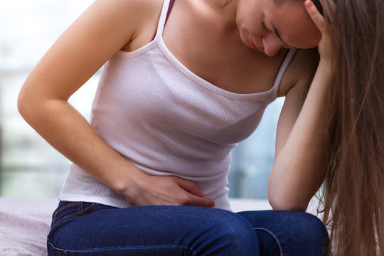 Young Woman Feels Bad And Experiences Abdominal Pain During The Period Of PMS And Menstruation. Painful Menstruation. Inflammation And Bladder Infection