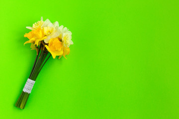 Bunch of yellow narcissus or daffodil flowers on green background. Place for text. Flat lay. Mother's day, easter, birthday