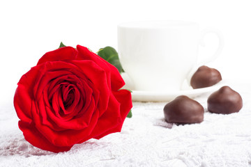 Beautiful red rose and cup of hot tea with chocolate