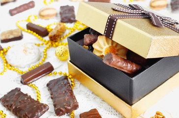 Golden box of chocolates, cookies and biscuits on  festive table