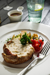 Pork with white mushroom sauce garnished with fried potatoes and cherry tomatoes.