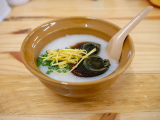 Rice porridge with century egg and ginger in a bowl on wooden background