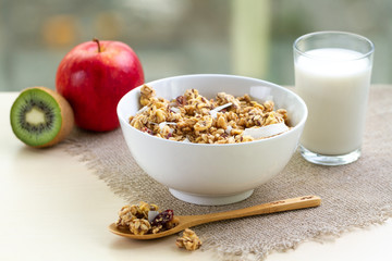 Dry breakfast cereals. Crunchy honey muesli bowl with flax seeds, cranberries and coconut and a glass of milk on a table. Healthy and fiber food. Breakfast time
