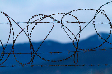 Barbed wire on mountains background in the evening.