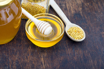 Honey with wooden honey dipper on wooden table