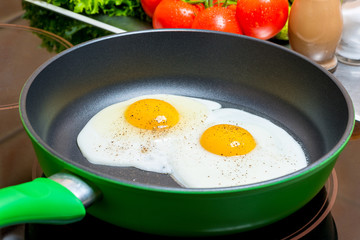 fried eggs in a frying pan fried on an electric plate close up