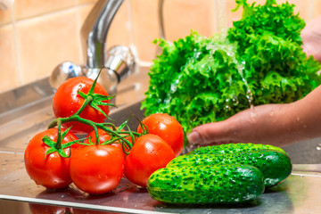 fresh clean washed vegetables on the background of a kitchen tap with flowing water
