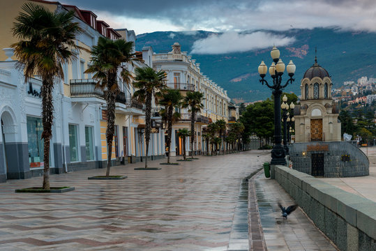 Embankment of the Russian city of Yalta in the autumn afternoon, view of the city and mountains