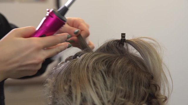 Curling hair styling and makeup for girl in beauty salon