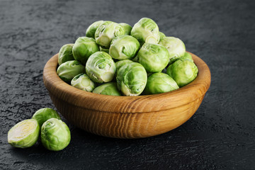 Wooden bowl with brussels sprouts on a dark background.