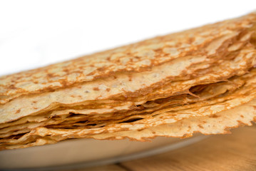 Close up on a stack of crepes (french pancakes) on a plate, white background