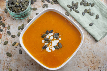 Home made pumpkin cream soup decorated with cream, seeds
