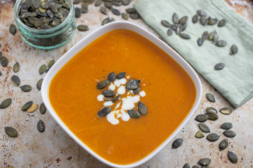Home made pumpkin cream soup decorated with cream, seeds