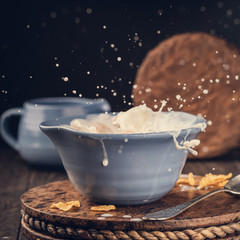 Blue bowl of corn flakes with milk splash. Healthy breakfast, highspeed photography. Toned.