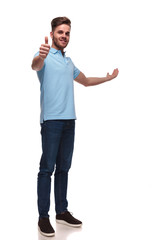 casual man presents to side while making thumbs up sign