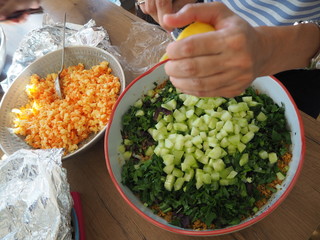 Housewife squeezing out a lemon on a bowl with salad in the kitchen.