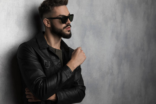 confident man wearing leather jacket and sunglasses looks to side