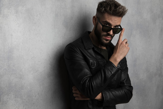 portrait of casual man in leather jacket touching his sunglasses