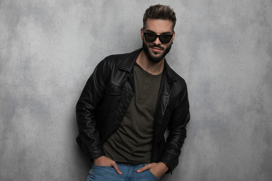 portrait of relaxed man wearing leather jacket and sunglasses smiling