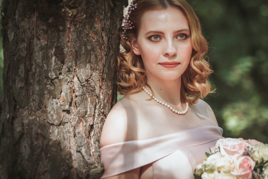 portrait of a beautiful bride standing near a tree
