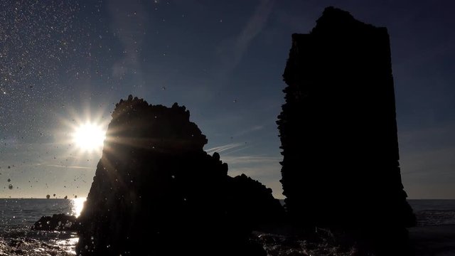 Back light near ocean with run-down tower and wave breaking
