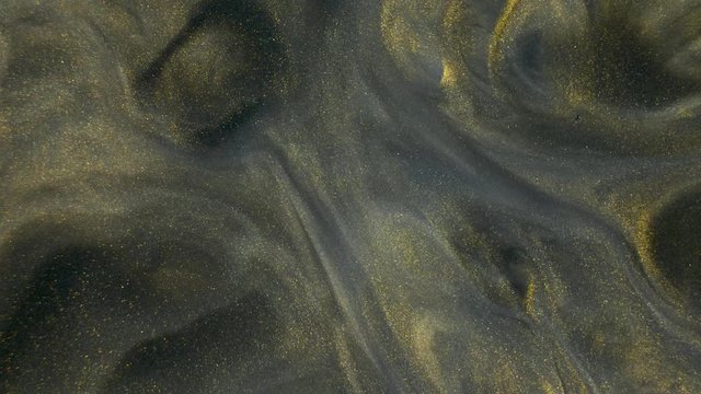 Colorful golden sand organically moves in colorful liquid
