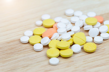 Colorful medicine pills tablets or drugs closeup on wood table background.