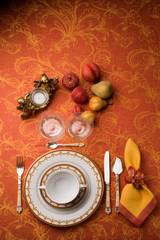 table service organized with orange background, with decoration of candles and fruits