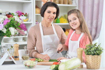 Obraz na płótnie Canvas Portrait of smiling mother and daughter cooking together at kitchen