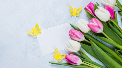 Spring Pink Tulips and Empty Paper Blank on blue stone background for Mother's Day, March 8. Easter Holiday Concept. Top view, flat lay, copy space