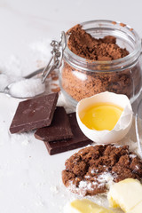 ingredients for baking chocolate chip cookies on white marble background close-up.