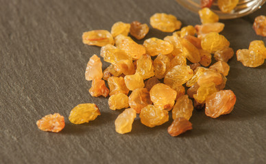 Close up of scattered tasty dried raisins and glass jar on tabletop in kitchen