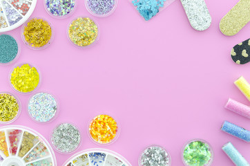 Bottles of Colorful nail glitters, color changing shining powder isolated on pink background. Manicure decoration glitter pigment set. Flat lay. Hero header rhinestones, sequins, crystals