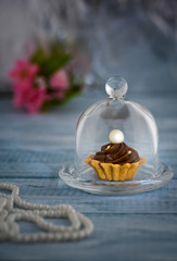 Cake miniature with a pearl under a glass cap on a background in the style of vintage