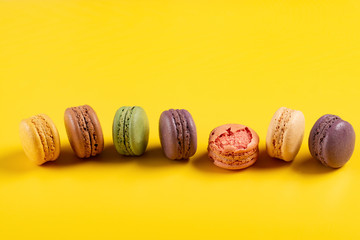 studio shoot of colorful macaroons line up on yellow background