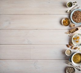 Different nuts, cereals, raisins on plates on a wooden table. Cedar, cashew, hazelnut, walnuts, almonds, pumpkin seeds, sunflower seeds, bulgur, buckwheat, rice and a spoon on the table.