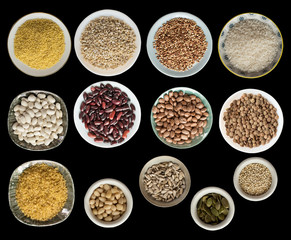Various cereals, seeds, beans, peas on plates isolated on black background, top view.