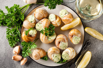 Escargots de Bourgogne - Snails with herbs butter on gray background. Top view