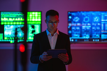 Fototapeta premium The businessman with a tablet standing on screens background