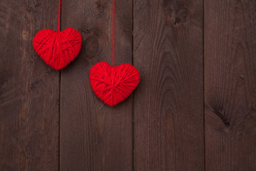 Two heart made of red wool yarn on wood background.Valentine's day concept.