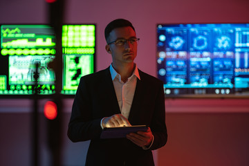 The businessman with a tablet standing on screens background