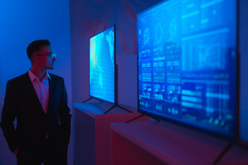Fototapeta premium The businessman standing near screens in the dark room