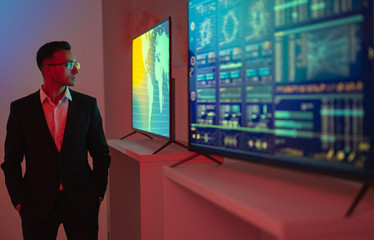 The businessman standing near screens with graphs