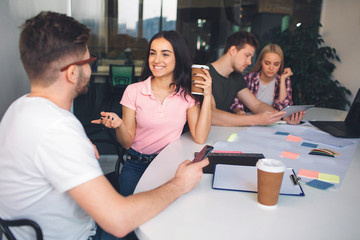 Happy and positive young brunette look at guy and smile. She hold cup of coffee. He look at her....