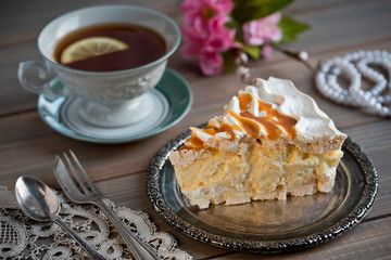 Slice of meringue cake and a cup of tea and flowers and pearls