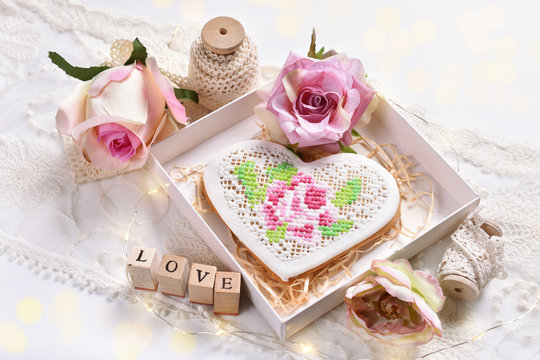romantic style flat lay with a heart shaped cookie and roses